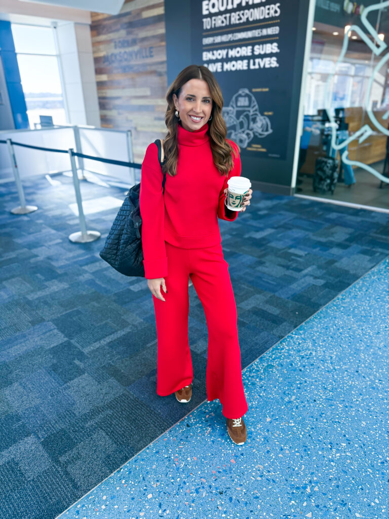 brunette woman in matching red sweater and pants at airport