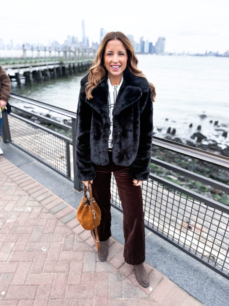 Brunette woman wearing velvet brown pants and black faux fur jacket in NYC