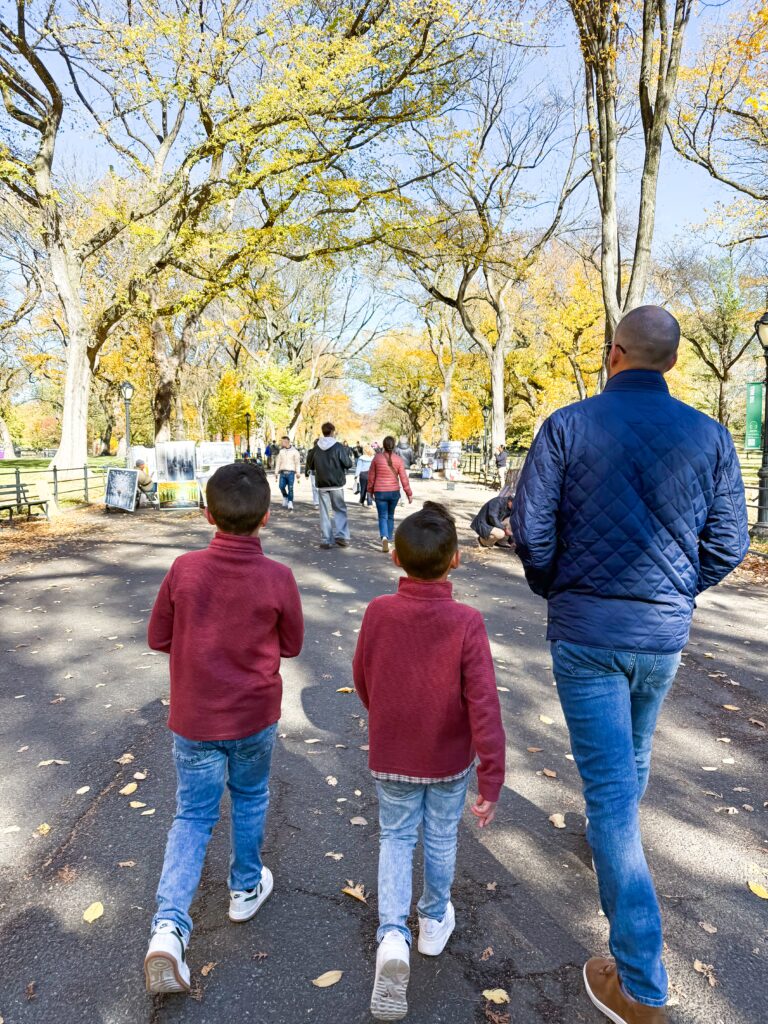 Father and two sons on NYC family trip walking in Central Park 