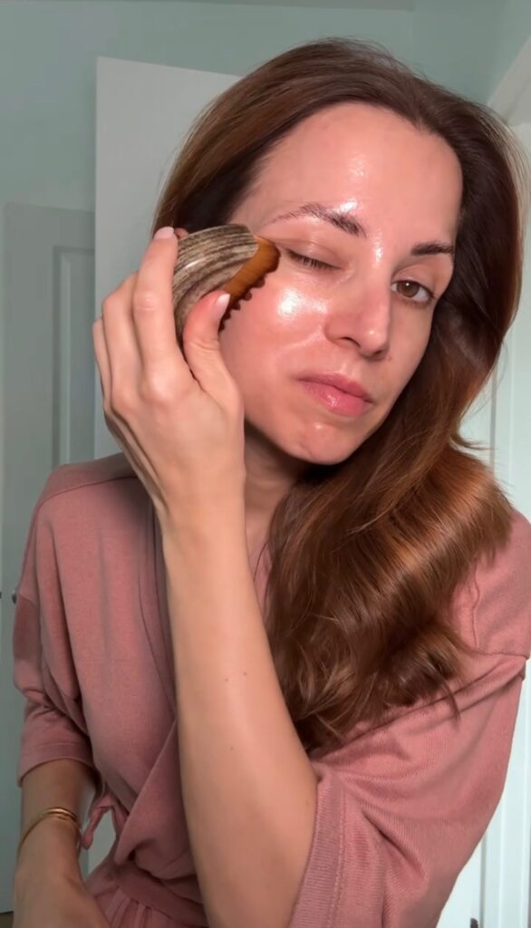 Brunette woman using a facial contour tool on upper cheek for lymphatic drainage as part of unsexy self-care things