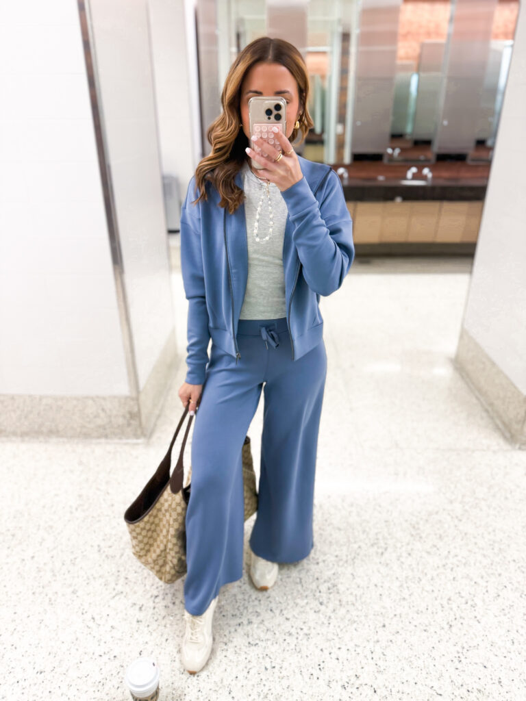 brunette influencer taking picture of blue matching set travel outfit