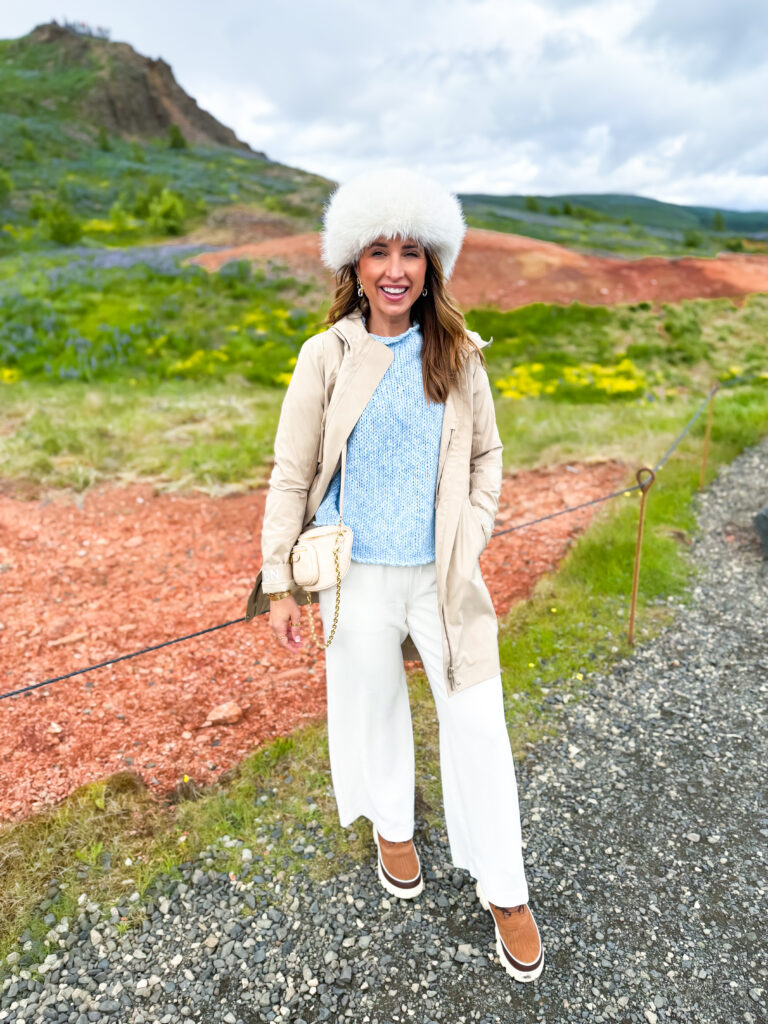 Woman in front of Icelandic backdrop wearing a fur hat and rain jacket in Europe